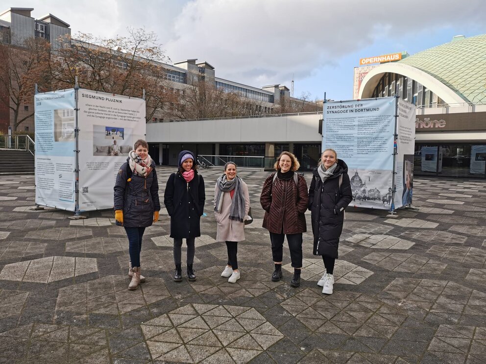 5 junge Frauen stehen draußen vor einem großen Gebäude
